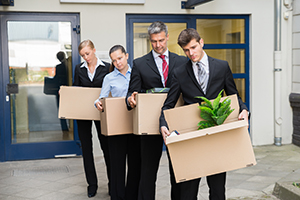 Disappointed Businesspeople Standing In A Row With Cardboard Boxes Outside The Office